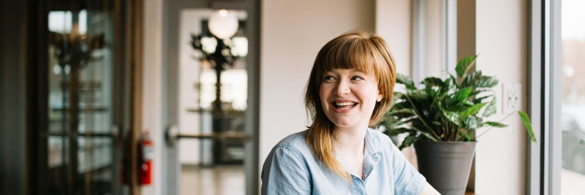 En kvinna i en korridor ser leende snett till vänster